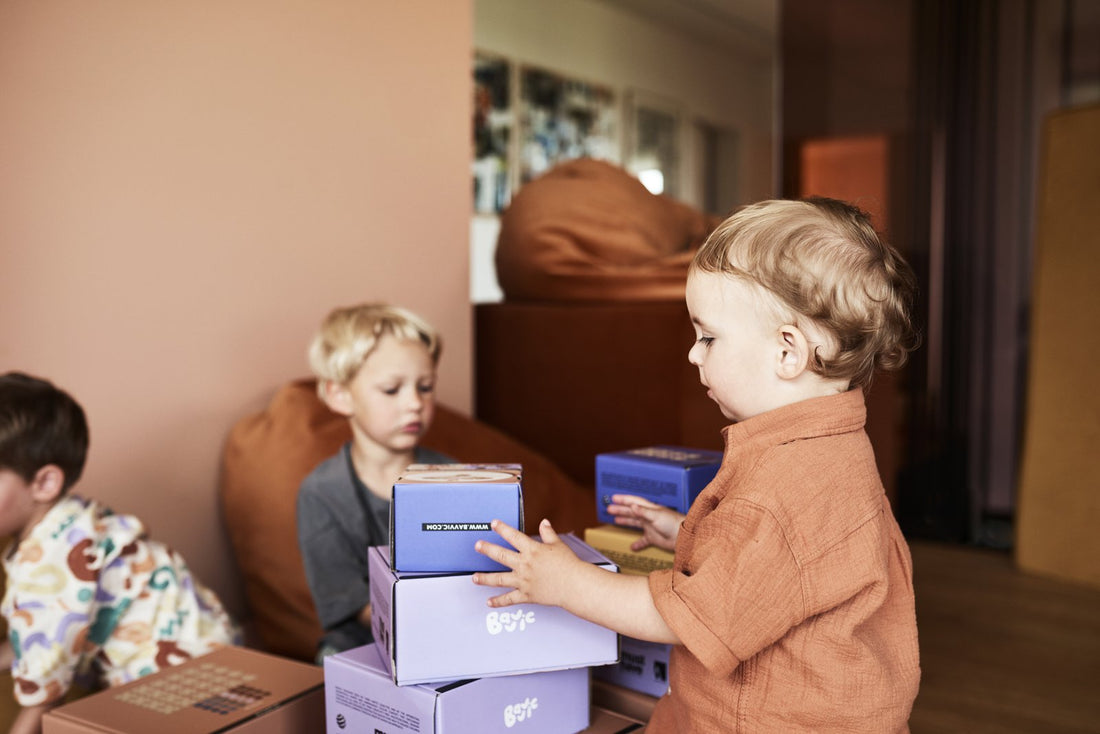 Three young children unpacking and stacking lilac BAVVIC set boxes together in a playroom